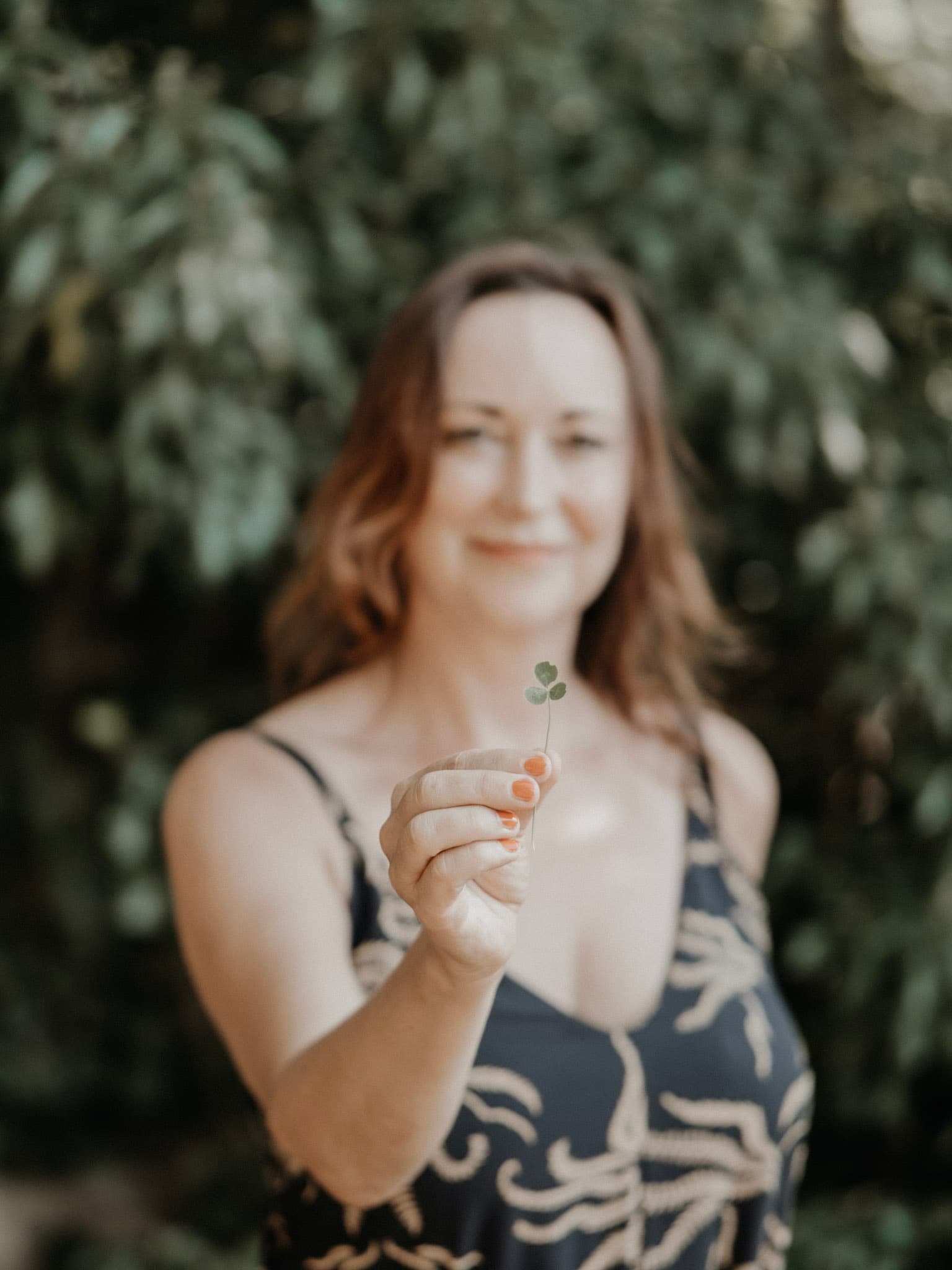 Anja Wolfram, Business Coach in Dresden, lächelnd vor grünem Blattwerk