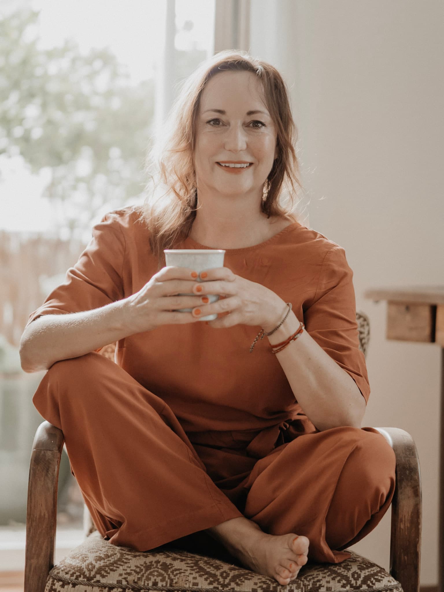 Anja Wolfram, Mental Health Coach aus Dresden, sitzt entspannt mit einer Tasse in der Hand