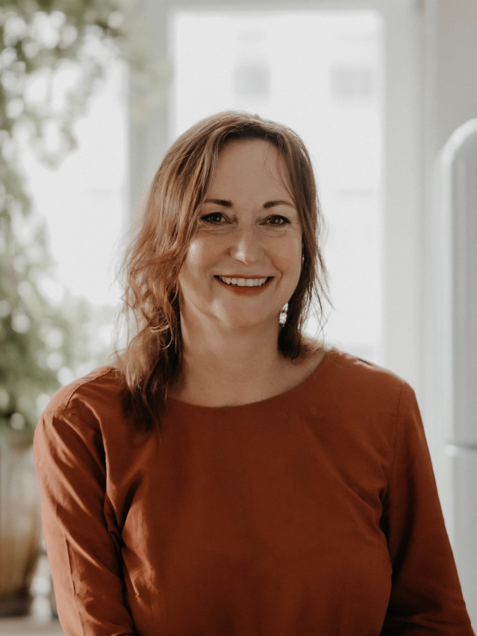 Anja Wolfram, lächelnd, im Gegenlicht am Fenster