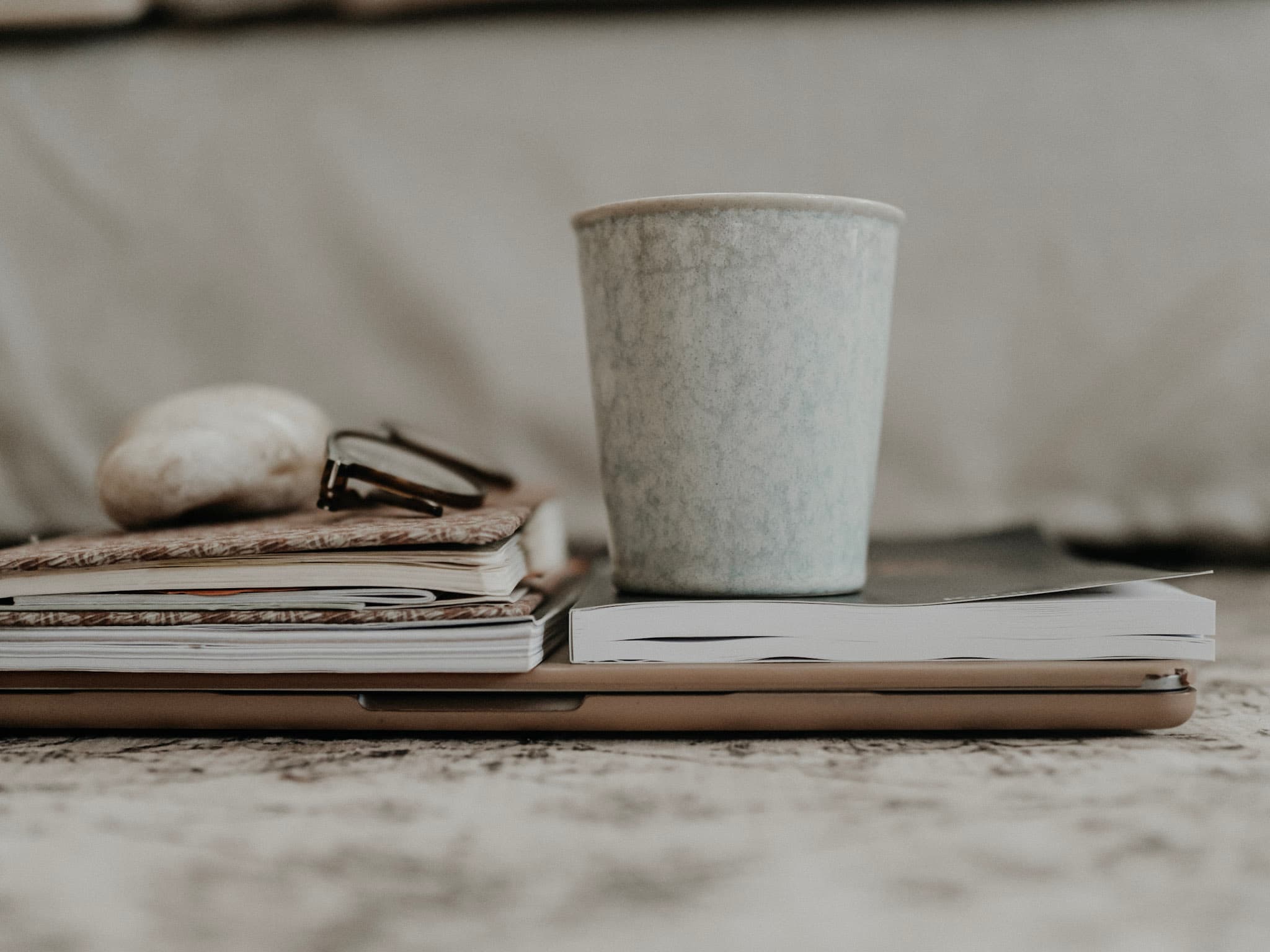 Becher, Notizbücher und eine Brille auf einem Tisch