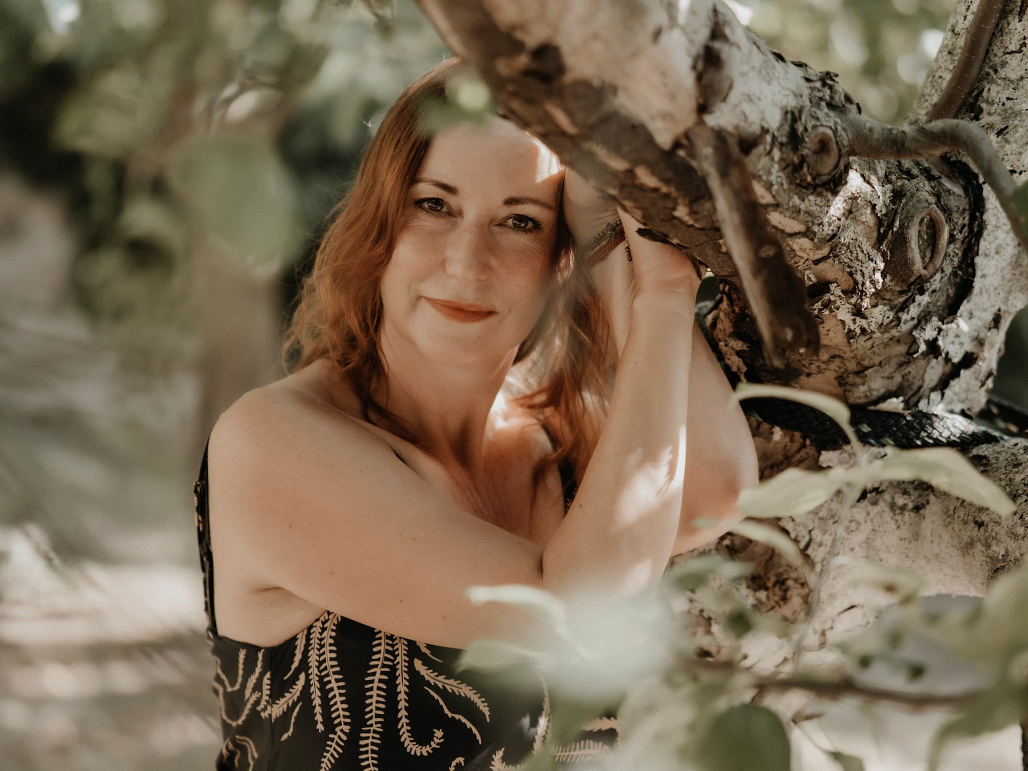 Anja Wolfram draußen an einem Baum, Sonnenlicht im Laub